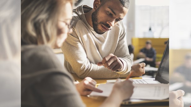 Två personer sitter vid ett bord. På bordet finns papper. Det tittar på det som ligger på bordet. Foto Istock