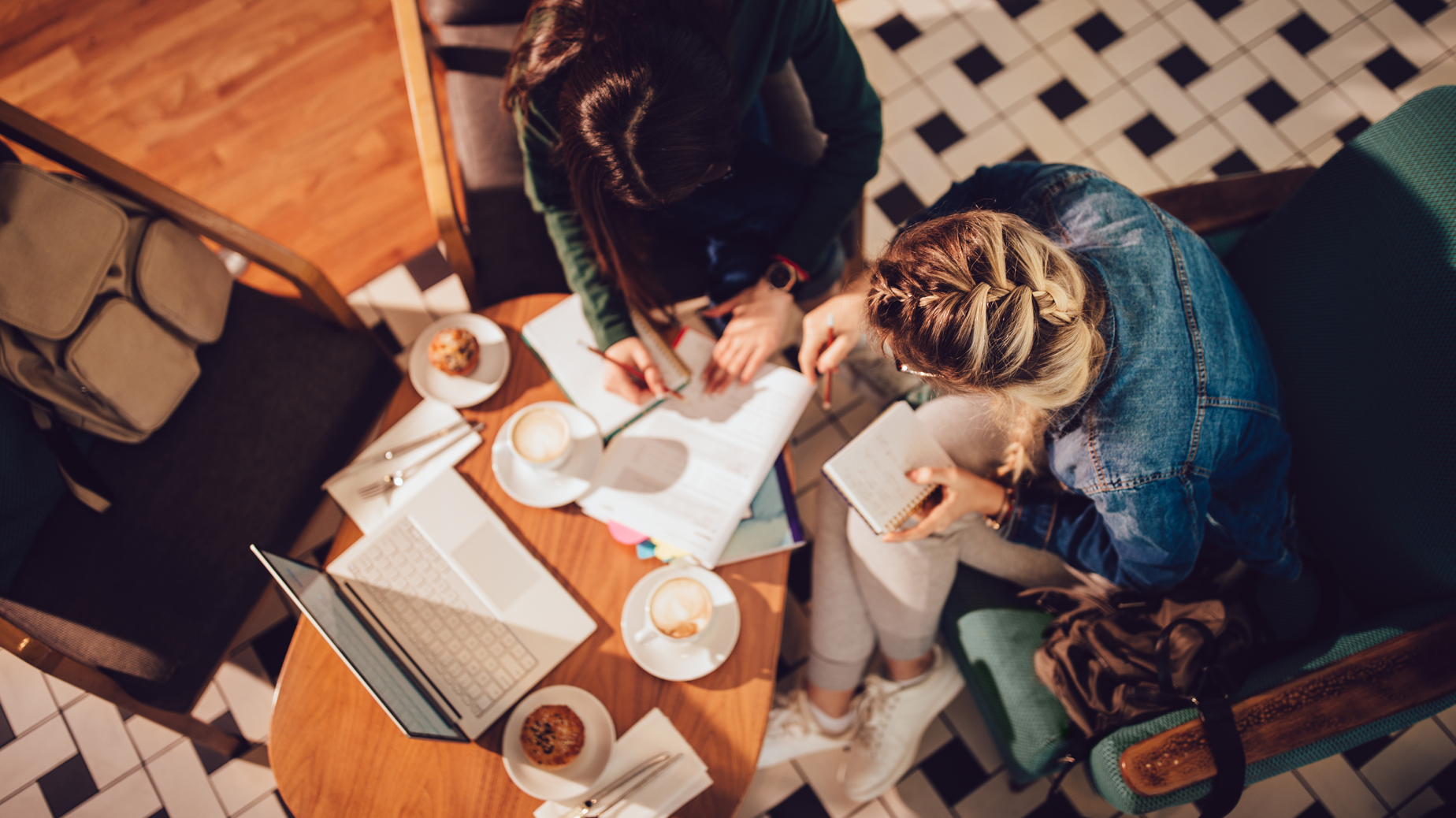 Studenter sitter vid runt bord. Böcker och dator på bordet. foto Istock