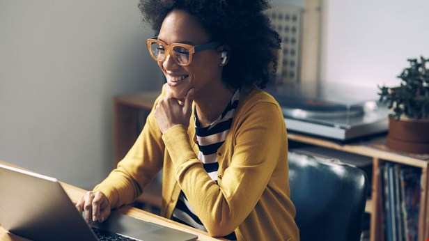 Kvinna leende framför laptop. Foto Istock